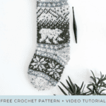 Crochet polar bear stocking with a geometric pattern, surrounded by greenery. Includes a crochet hook and text advertising a free pattern and video tutorial.