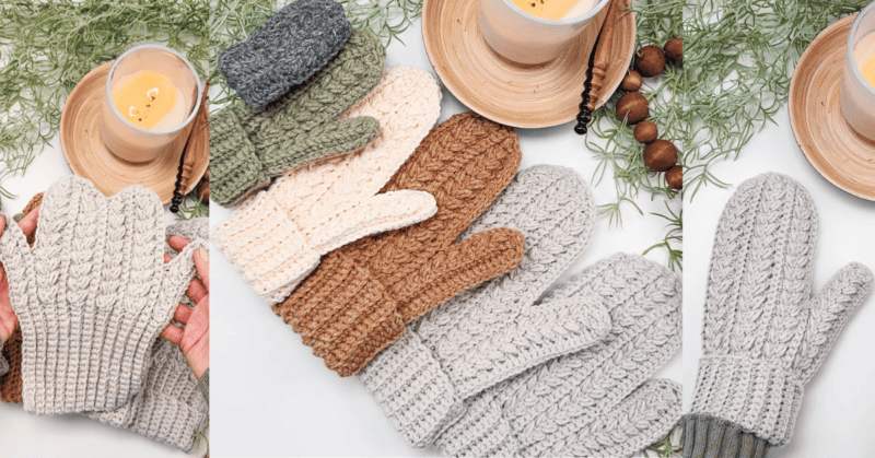 Several pairs of knitted mittens in various colors are displayed on a surface, accompanied by a candle, a cup, and green foliage.