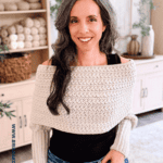 Woman modeling a cream crochet sweater scarf in a living room; text on image promotes the free Winter Wheat Crochet Sweater Scarf Pattern, video, and nine available sizes.