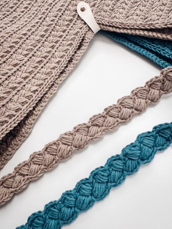 Close-up of textured knitted beige fabric with a white tag, and two braided ropes, one beige and one blue, laid parallel on a white surface.