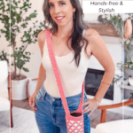 Woman wearing a cream tank top and jeans models a pink Free Crochet Water Bottle Holder worn across her body in a cozy living room setting.