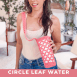 A woman stands indoors holding a pink Free Crochet Water Bottle Holder with a crossbody strap. Text on the image promotes a free crochet pattern and video tutorial at brianakdesigns.com.
