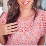 Woman wearing a pink lace crochet summer top, smiling at the camera with hand raised near her neck. Text overlay reads, "Lace Summer Top You’ll Actually Wear." Perfect for your next project—get the free crochet pattern summer top now!.