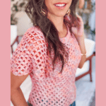 Woman wearing a pink crocheted lace summer top, standing indoors and smiling. Text on the image promotes a free crochet pattern summer top available at brianakdesigns.com.