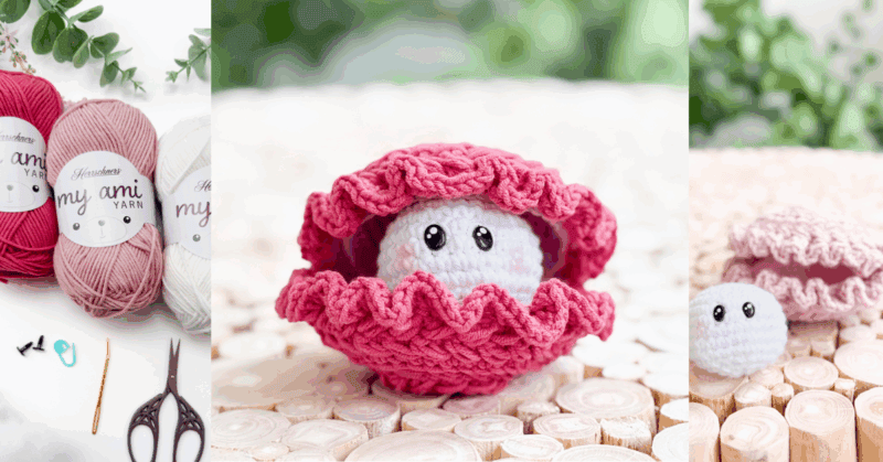 A crocheted pink clam shell with a white, round creature featuring black eyes sits open on a wooden surface, surrounded by yarn and crochet tools.