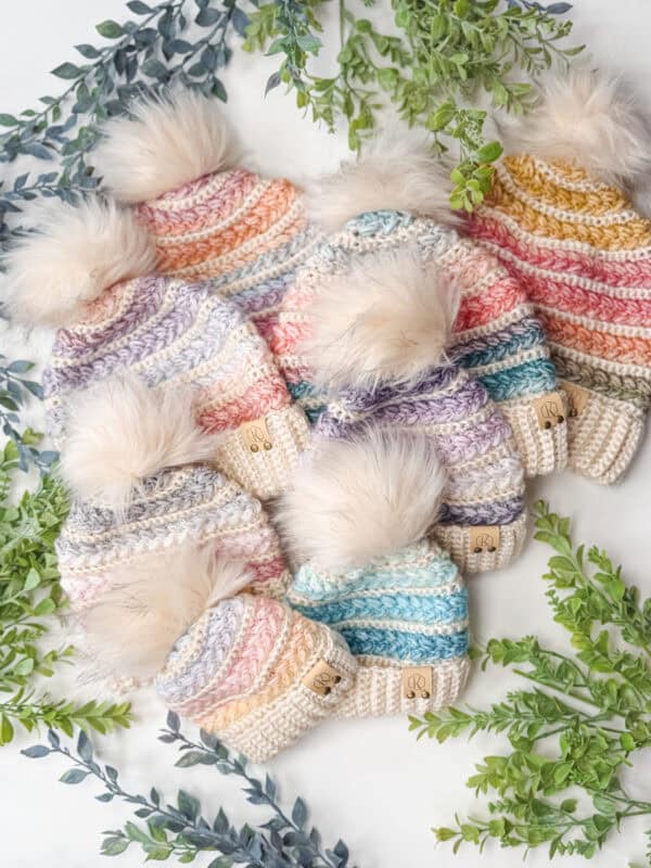 A group of knit hats with pompoms, including a stylish Wheat Stitch Crochet Beanie.