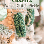 Close-up of a crocheted green pickle ornament hanging on a Christmas tree, with text promoting a free Wheat Stitch Crochet Pickle Ornament Pattern and video tutorial for making this festive decoration.