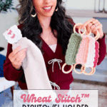 A woman holds a knit dish towel with a crocheted holder in one hand and several colorful Wheat Stitch napkin ring crochet pattern holders with wooden rings in the other. Text reads, “Wheat Stitch™ Dishtowel Holder Free Pattern + Video Tutorial.”.