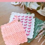 Three crocheted hotpads in pink, white, and green with scalloped edges displayed on a wooden surface. Text offers a free wheat stitch hotpad pattern and video tutorial.