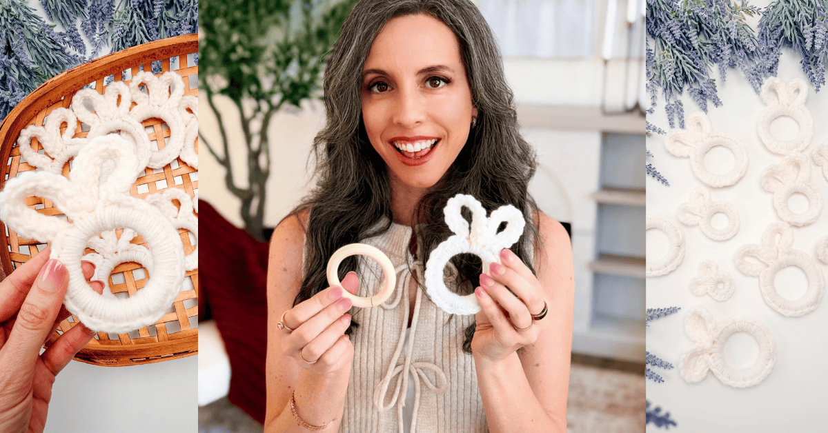 A woman holds up a wooden ring and a handmade white yarn ornament shaped like a crochet bunny head with ears, with several similar ornaments displayed nearby.