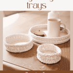 Three woven trays of varying sizes, inspired by a crochet nesting trays pattern, hold a cup, wooden coaster, and jar on a wooden table. Text reads: "sturdy & stylish trays you'll actually use.