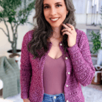 Woman wearing a purple crochet cardigan crafted from a stylish crochet cardigan pattern over a matching top and jeans, standing indoors with plants in the background. Text reads "The Cardigan You'll Wear Every Day.