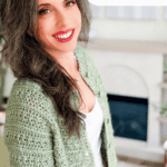 Woman wearing a green crocheted cardigan stands indoors, smiling at the camera. Text reads "You Can Crochet This!"—the perfect crochet cardigan pattern for your next project.