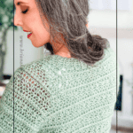 Woman wearing a light green crochet sweater with intricate, repeating textured stitches, looking over her shoulder. Text reads "Beautiful Texture" and "Easy Stitch Repeat." Discover this stylish crochet cardigan pattern today.
