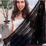 A woman stands indoors holding a large, black, lacy crocheted wrap. Overlay text reads, “The wrap you’ll wear every day” and “Lightweight + Lacy.” Inspired by our Willow Mesh Stitch crochet tutorial.