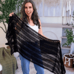 A woman stands indoors holding a large, black crocheted shawl. Text reads: "Relaxing Crochet Project" and "You'll Actually Finish." Features a Willow Mesh Stitch crochet tutorial.