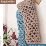 Two crocheted bag holders, one beige and one light blue, hang on hooks next to a potted plant; a tag and label mention a free crochet pattern.