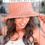 Woman wearing a pink crochet sun hat and striped dress, smiling and holding the brim of her hat. Text reads “Wheatfield Crochet Sun Hat.”.