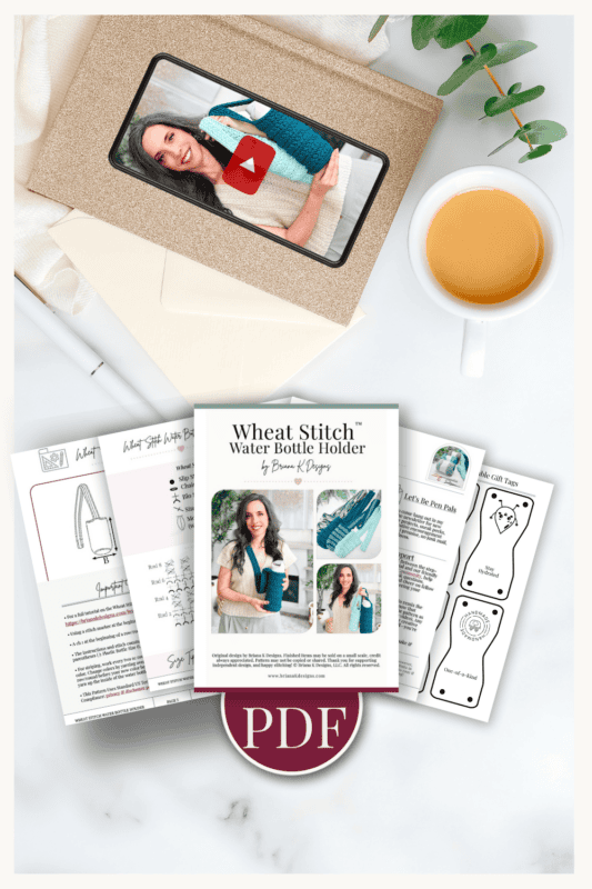 A printed PDF tutorial for a wheat stitch water bottle holder, crochet pattern pages, a cup of coffee, a pen, and a tablet displaying a woman with a yarn project.