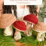 A person holds a wooden tray with crocheted mushrooms and green ferns. Text reads: "How to Crochet: Wheat Stitch Mushrooms. Step-by-Step Video Tutorial + Free Pattern.
