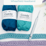 Two skeins of blue yarn, a crochet hook, darning needle, and finished headbands are displayed under a "Crochet a Headband" video tutorial sign featuring a free crochet tie headband pattern.