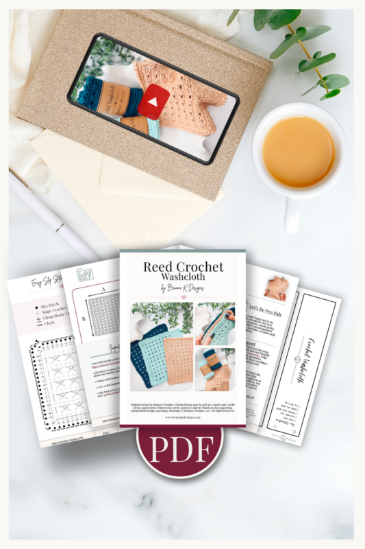 Flat lay of crochet pattern pages, a Reed Crochet Washcloth pattern cover, a cup of tea, greenery, and an envelope with a photo and play button, emphasizing PDF format.