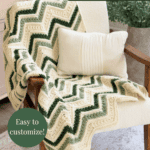 A cream armchair with a green and cream chevron crochet blanket draped over it, accompanied by a white pillow. Text promotes a customizable petal loop stitch crochet pattern.