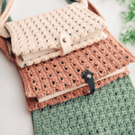 Three crocheted book covers in beige, pink, and green are stacked on a white surface. Each cover has a button closure and a strap. Text on the image promotes a free crochet pattern and tutorial.