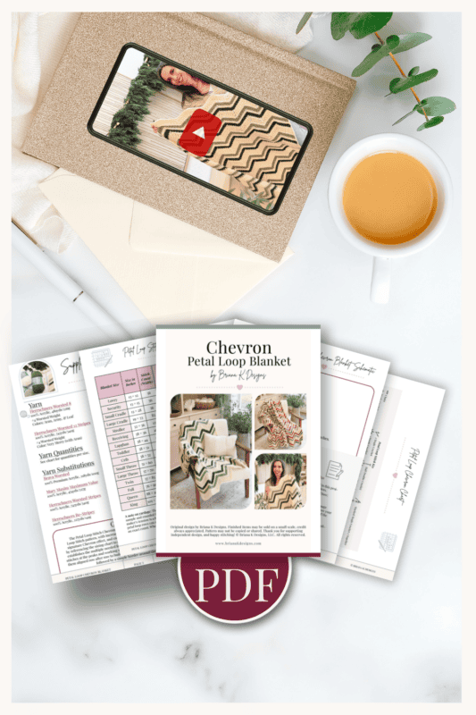 A PDF pattern for a chevron petal loop blanket is shown with printed pages, a cup of tea, an envelope, and a plant on a white surface.