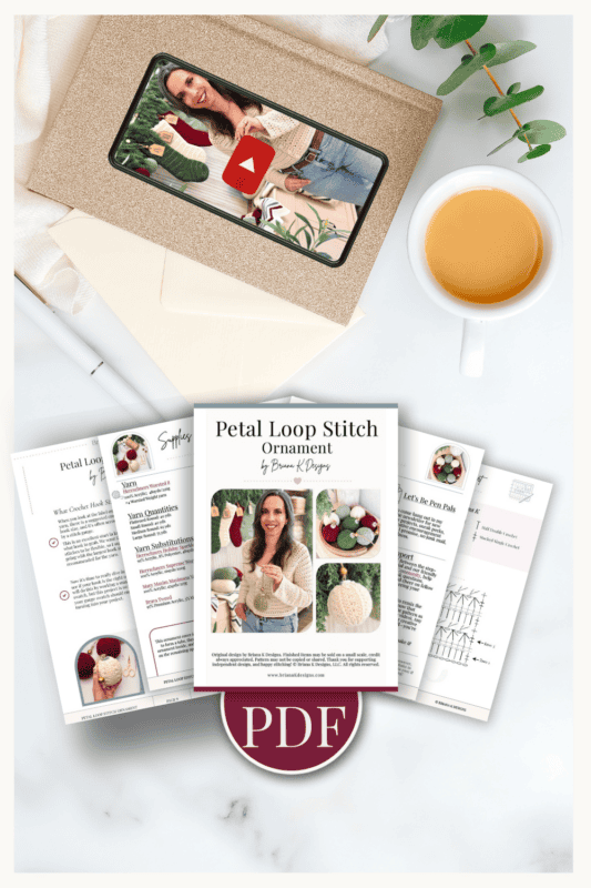 Flat lay of a crochet pattern PDF titled "Petal Loop Stitch Ornament" with a mug of tea, an envelope, a pen, greenery, and a photo of a woman holding a crochet ornament.