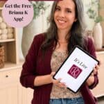 Woman holding tablet with “It’s Live” displayed, promoting the launch of the Briana K Designs App for phone pattern access.