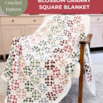 A multicolored crochet granny square blanket drapes over a wooden chair in a bright room with light cabinets and potted plants.