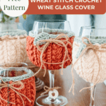 Four wine glasses on a wooden surface, each with a knitted wheat stitch crochet cover in cream or rust colors, tied with twine bows. A label advertises a free pattern for the covers.