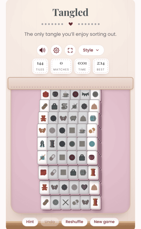 A digital tile-matching game called “Tangled” is in progress, showing stacked tiles with sewing-themed icons and game stats above, evoking the charm of a crochet solitaire game.