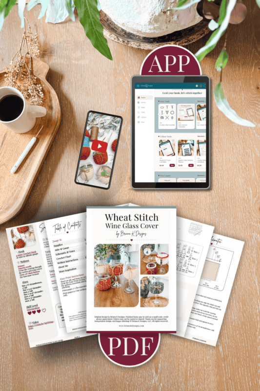 Tablet displaying an app, smartphone, coffee cup, and printed craft instructions for a wheat stitch wine glass cover, arranged on a wooden table with leaves and dried flowers.