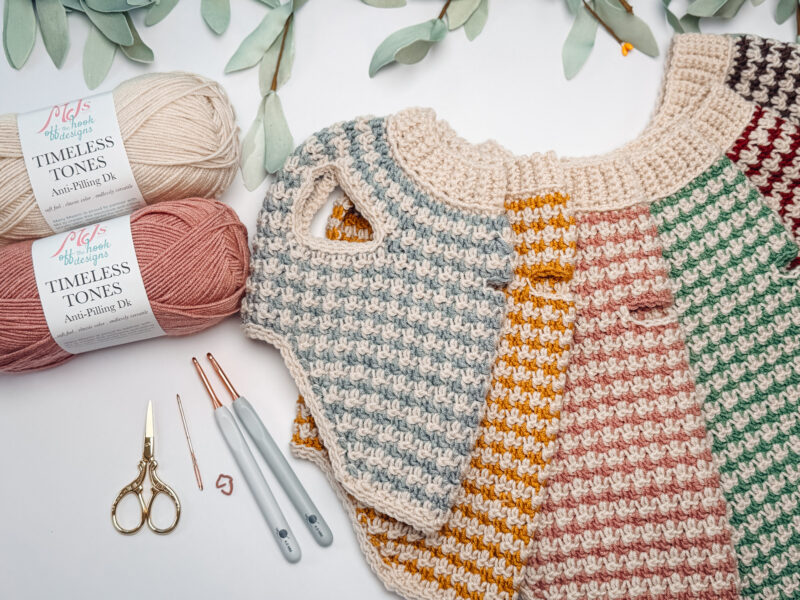 Two skeins of yarn, a pair of scissors, crochet hooks, and several crocheted swatches in variegated colors.