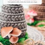 A gray wheat stitch crochet witch hat decorated with artificial mushrooms, moss, and twine.