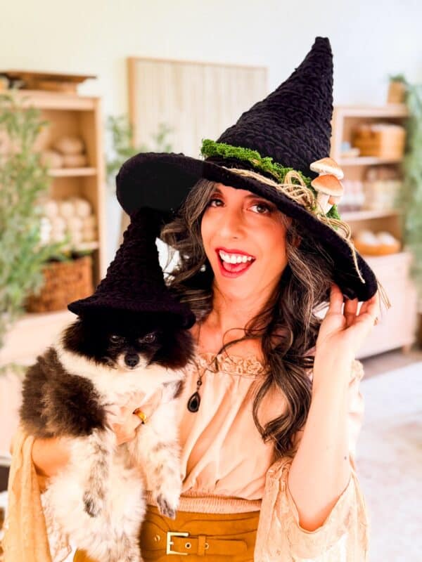 Briana K in a black Wheat Stitch witch hat holding her dog in a tiny matching witch hat
